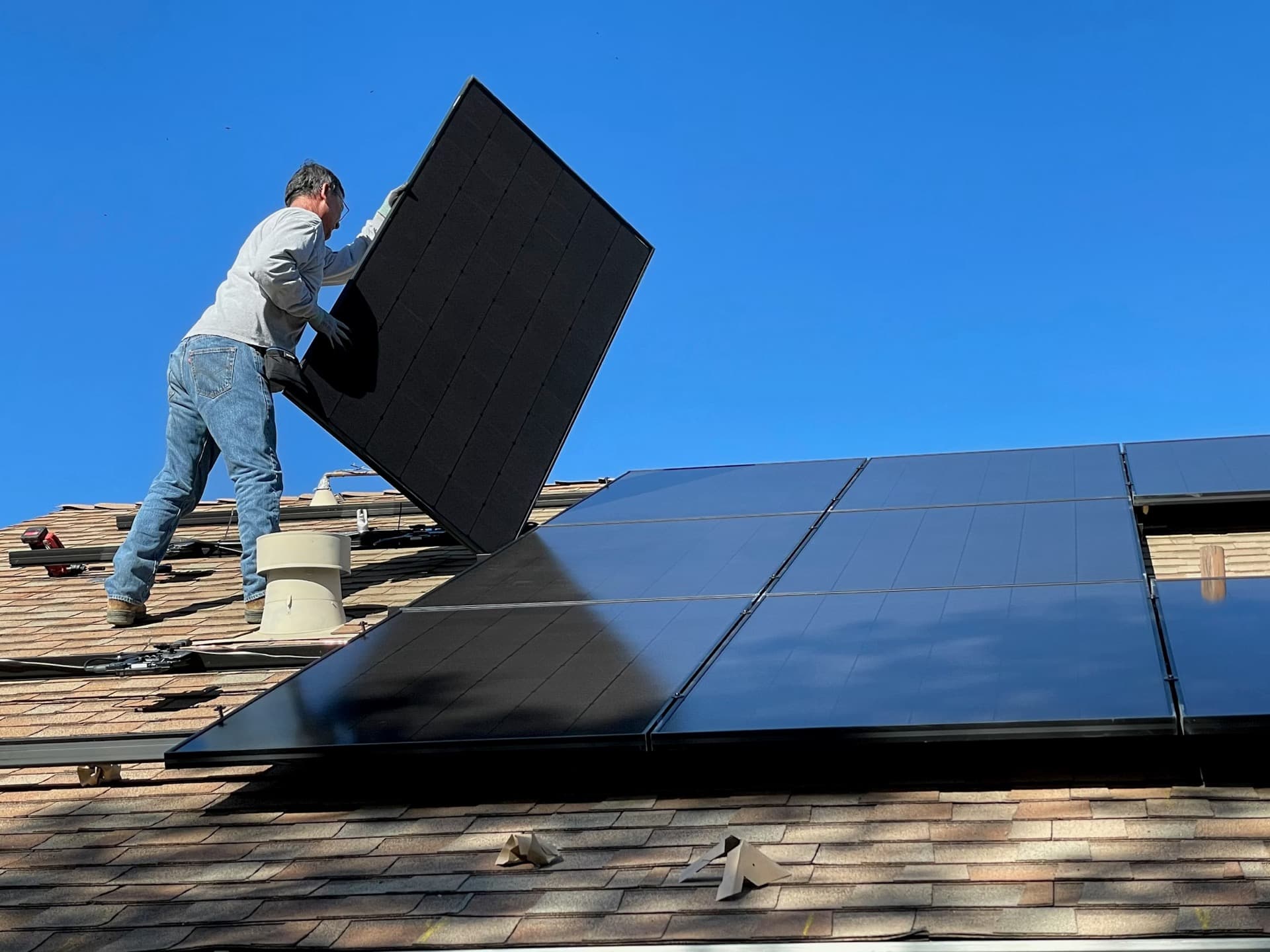 Installer placing a solar panel on a residential roof