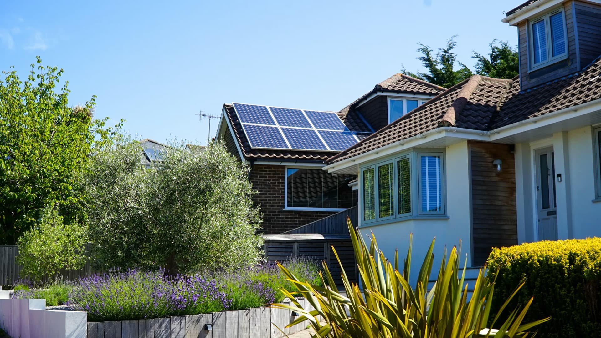 Home with solar panels installed on rooftop in sunny garden