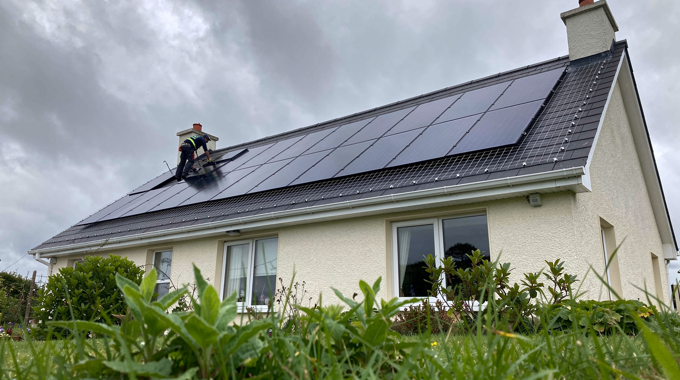 Worker installing bird proofing mesh around solar panels on Irish house roof