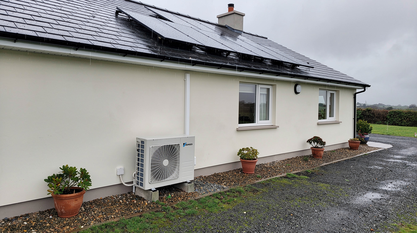 Air-to-water heat pump unit beside an Irish bungalow with solar panels on the roof