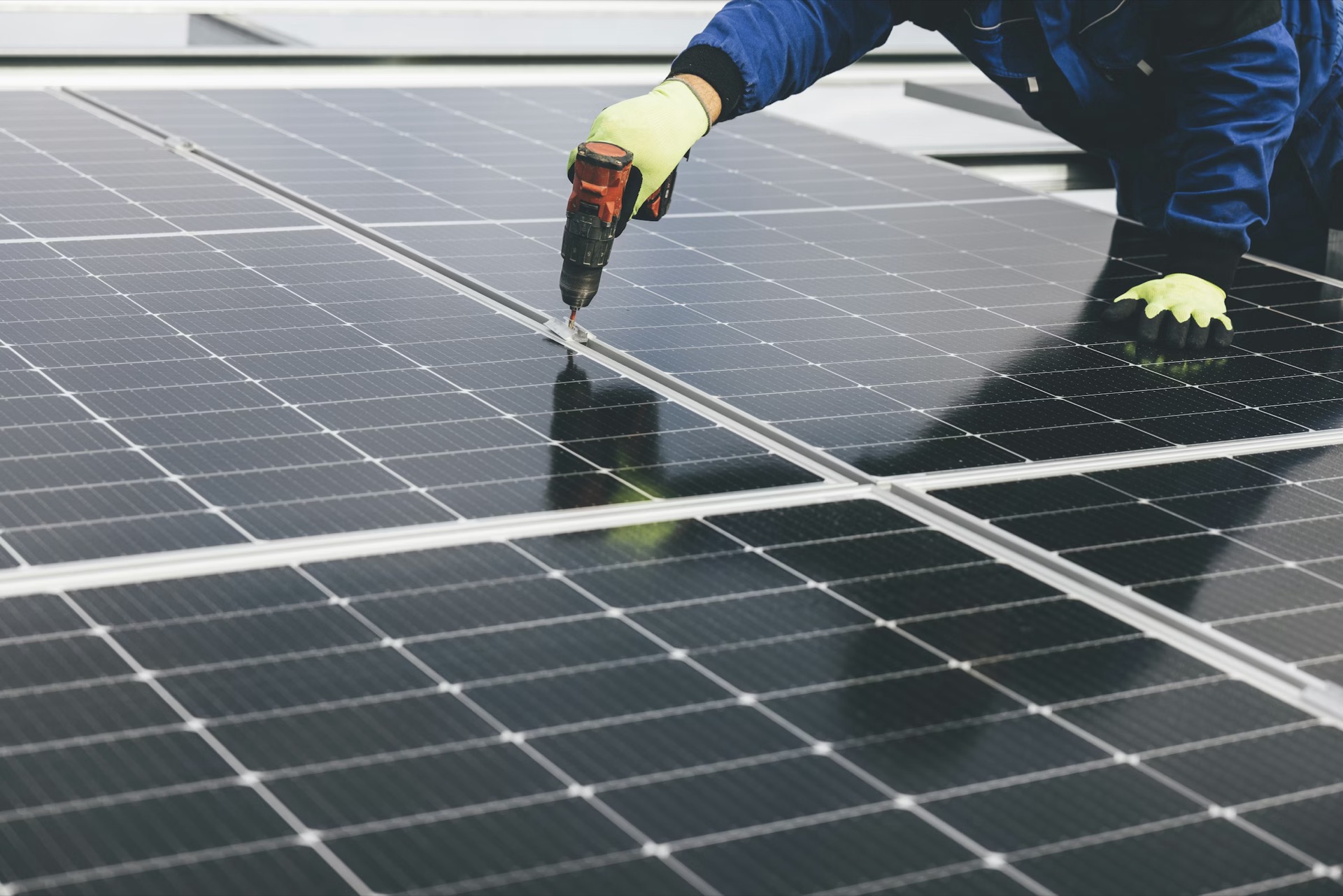 Technician securing solar panels with a drill